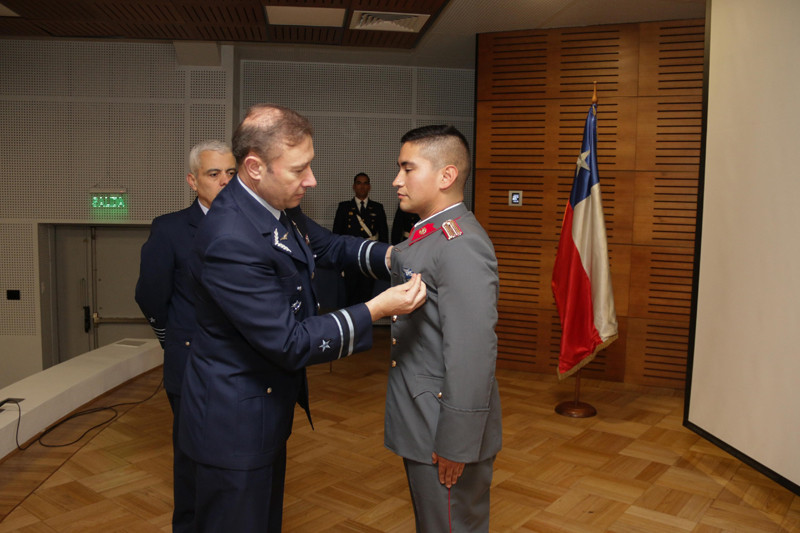 El general de brigada aérea Guillermo Pino entrega al alférez José Rojas la piocha roja de piloto militar. Firma FACh